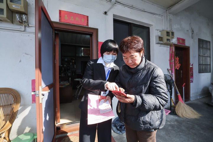 2025年12月18日,浙江省诸暨市东白湖镇事业综合服务中心的党员志愿者(左)上门“一对一”指导村民使用“浙里办”数字化平台办理业务。新华社记者 徐昱 摄